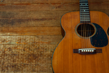 Naklejka premium Vintage Acoustic Guitar on a Hardwood Floor.