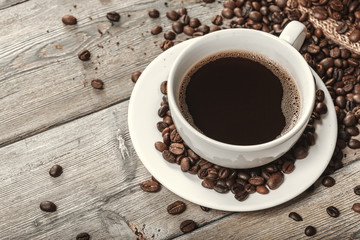Cup of coffee and beans on wooden background