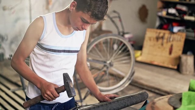 Teenager hammering bicycle wheel