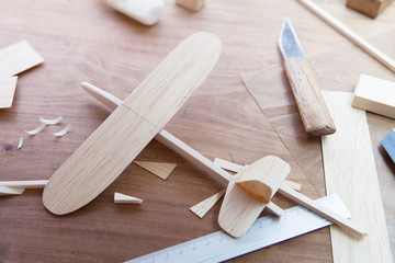 Making model airplane from wood. Wooden air plane handcrafted with balsa wood, on work table by the...