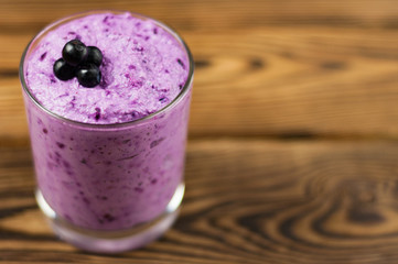 One full glass of homemade smoothies with blueberries on rustic wooden table with copy space. Cookery concept