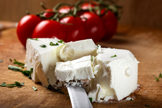 Pieces of white cheese on a wooden cutting board with cherry tomatoes