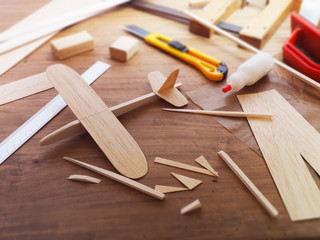 Making model airplane from wood. Wooden air plane handcrafted with balsa wood, on work table by the...