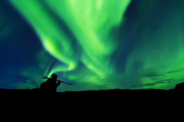 Naklejka na ściany i meble Aurora borealis with silhouette standing photographer on the mountain.Freedom traveller journey concept
