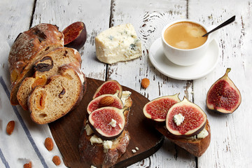 Sandwich with figs, cheese and a Cup of coffee on a wooden background.