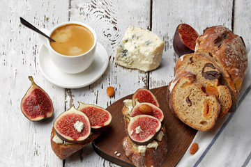 Sandwich with figs, cheese and a Cup of coffee on a wooden background.