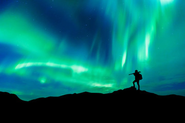 Aurora borealis with silhouette standing photographer on the mountain.Freedom traveller journey...