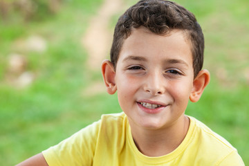 Portrait of happy smiling child boy outdoors. Concept of happy family or successful adoption or parenting.