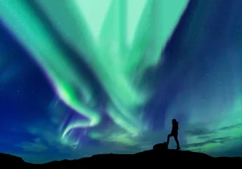 Fototapeten Aurora borealis with silhouette standing man on the mountain.Freedom traveller journey concept © basiczto
