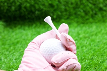 Hand of lady golfer is holding tee and golf ball 