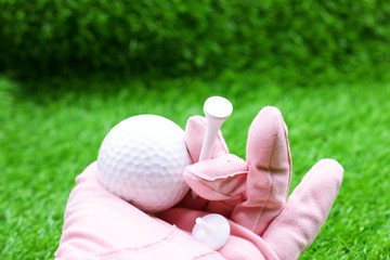 Hand of lady golfer is holding tee and golf ball 