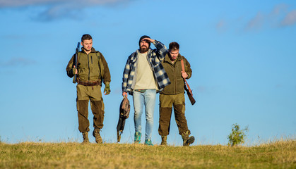 Hunting as hobby and leisure. Hunters with guns walk sunny fall day. Brutal hobby. Guys gathered for hunting. Group men hunters or gamekeepers nature background blue sky. Men carry hunting rifles