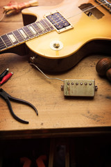 Electric guitar repair. Vintage electric guitar on a guitar repair shop work bench. gold color....