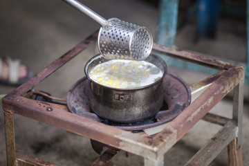 The background of the cooking on the gas stove, the use of long-handled spoon to cook, saw by rural attractions.