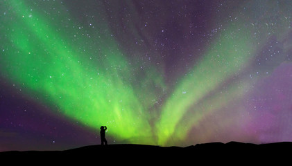 Fototapeta na wymiar Aurora borealis with silhouette standing man on the mountain.Freedom traveller journey concept