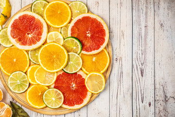 Mixed Fresh slices citrus fruit on a round wooden Board on a light background. Top view. With copy space