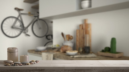 Wooden vintage table top or shelf with candles and pebbles, zen mood, over blurred contemporary white kitchen, minimal architecture interior design