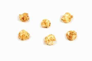 Few pieces caramel popcorn on white background.