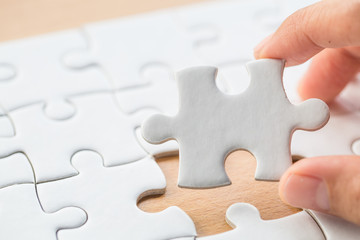 Fototapeta premium Hand put the last piece of jigsaw puzzle to complete the mission.