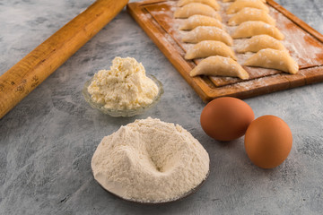Flour on a round plate, chicken eggs, cottage cheese-ingredients for cooking dumplings with filling.