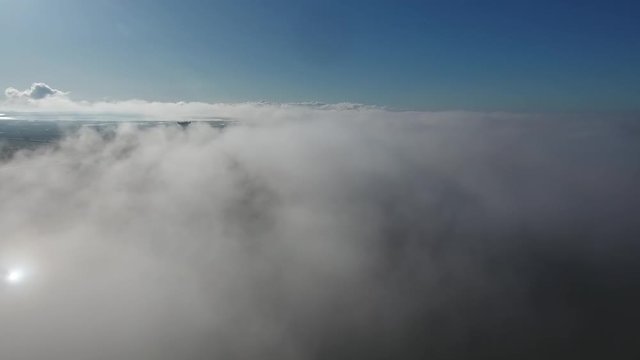 Drone shot moving forward over clouds in south of France, fields and vineyards u