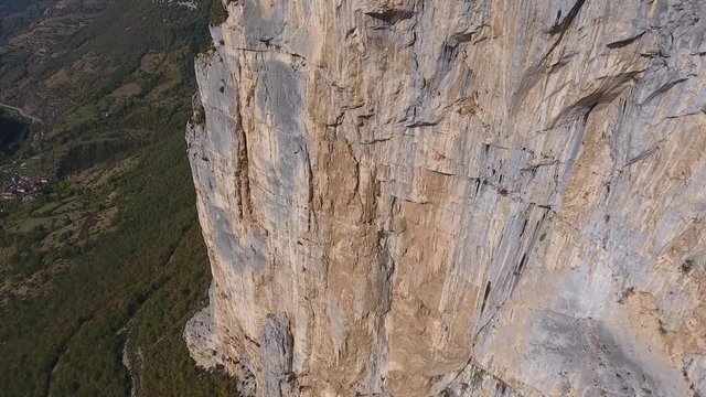 Aerial shot flying along a cliff in vercors massif, discovering three man on the top. Sunny day in choranche france.