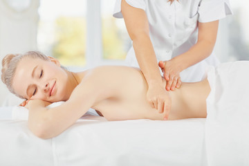 Fototapeta na wymiar Body massage. Beautiful blond woman in spa salon doing body massage.