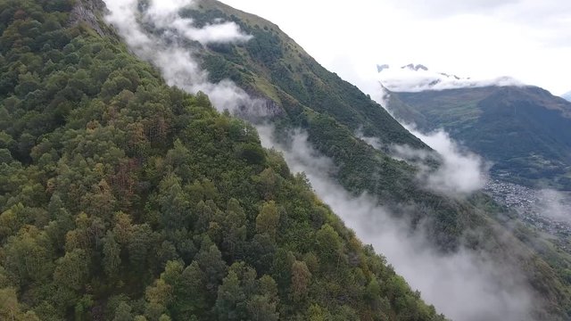 Cinematic drone shot flying toward a mountain with clouds in the Pyrenees, location France. Cloudy day.