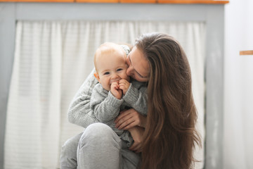 mother and baby son hug and kiss, real interior