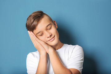 Sleepy teenage boy on color background