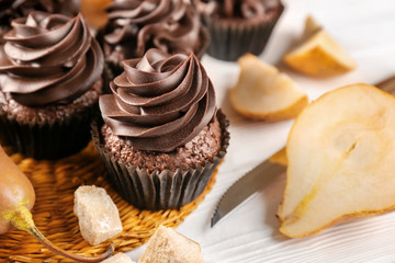 Chocolate cupcakes and pears on wooden table