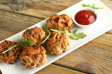 Plate with tasty sausage balls on wooden table