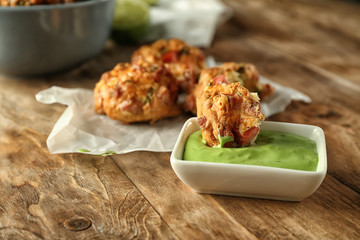 Tasty sausage balls and bowl with sauce on wooden table