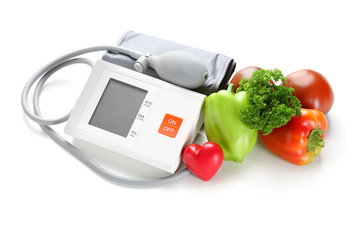 Sphygmomanometer with red heart and vegetables on white background