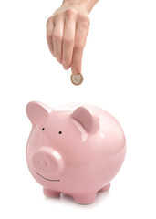 Woman putting coin into piggy bank on white background