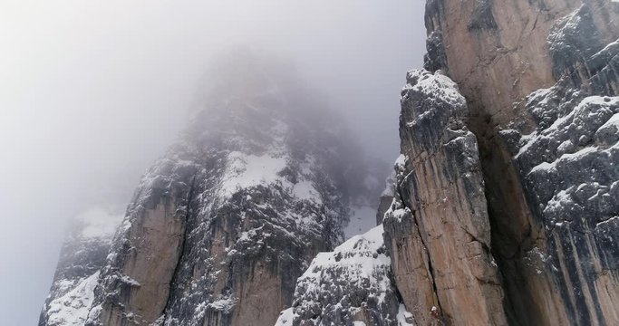Forward aerial to snowy rocky mountain.Cloudy bad overcast foggy weather.Winter Dolomites Italian Alps mountains outdoor nature establisher.4k drone flight