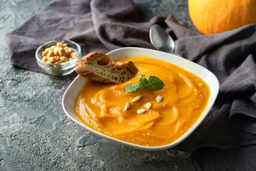 Plate with tasty pumpkin cream soup on grey table