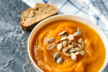 Bowl with tasty pumpkin cream soup on grey table, closeup