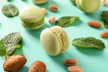 Tasty macaroons with mint and nuts on color background, closeup
