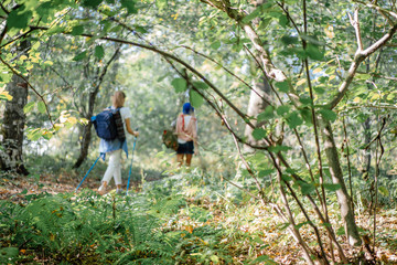 Young couple having a walk with nordic sticks on hike in the forest