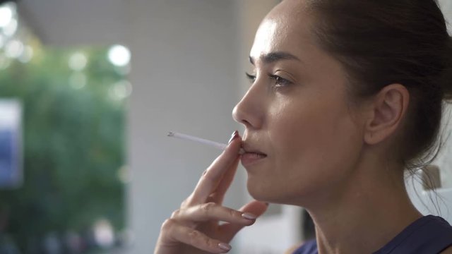 Beautiful woman smoking a cigarette outdoors close up
