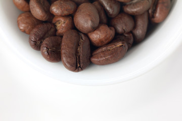 natural 100 percent/ plurality of roasted coffee beans inside the cup top view