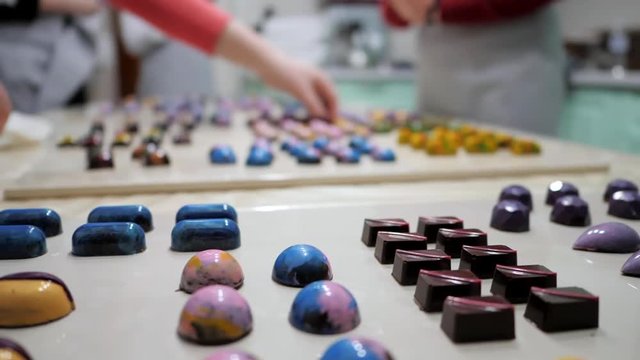 Set of colorful luxury handmade bonbons on white table. Exclusive handcrafted chocolate candies. Product concept for chocolatier. Homemade dessert preparing by women.