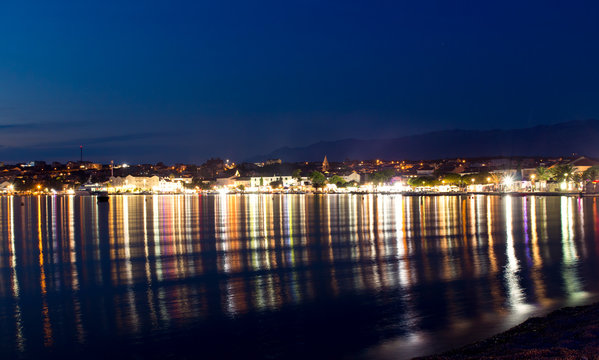 Town of Novalja at night and light reflections in the water, Croatia, Adriatic sea