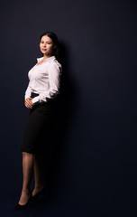 Full length portrait of a young beautiful businesswoman isolated on dark background. Woman in business concept.