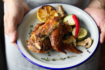 plate of baked chicken, lemon and vegetables.