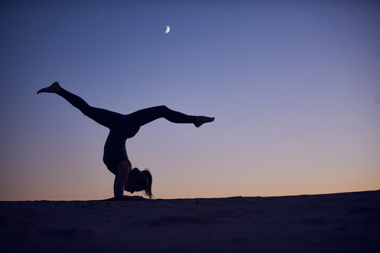 Beautiful Young Woman Practices Inverse Forearm Stand Yoga Asana Vrischikasana Scorpion Pose In The Desert At Night