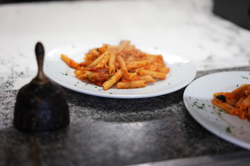 Zwei Teller mit Penne stehen an auf der Durchreiche und warten darauf vom Servicepersonal abgeholt zu werden um es im Restaurant zu servieren