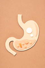 top view of human stomach with different pills on beige