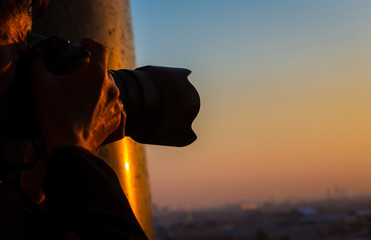 close up senior man photographer he's shooting picture with sunset sky scene on the roof